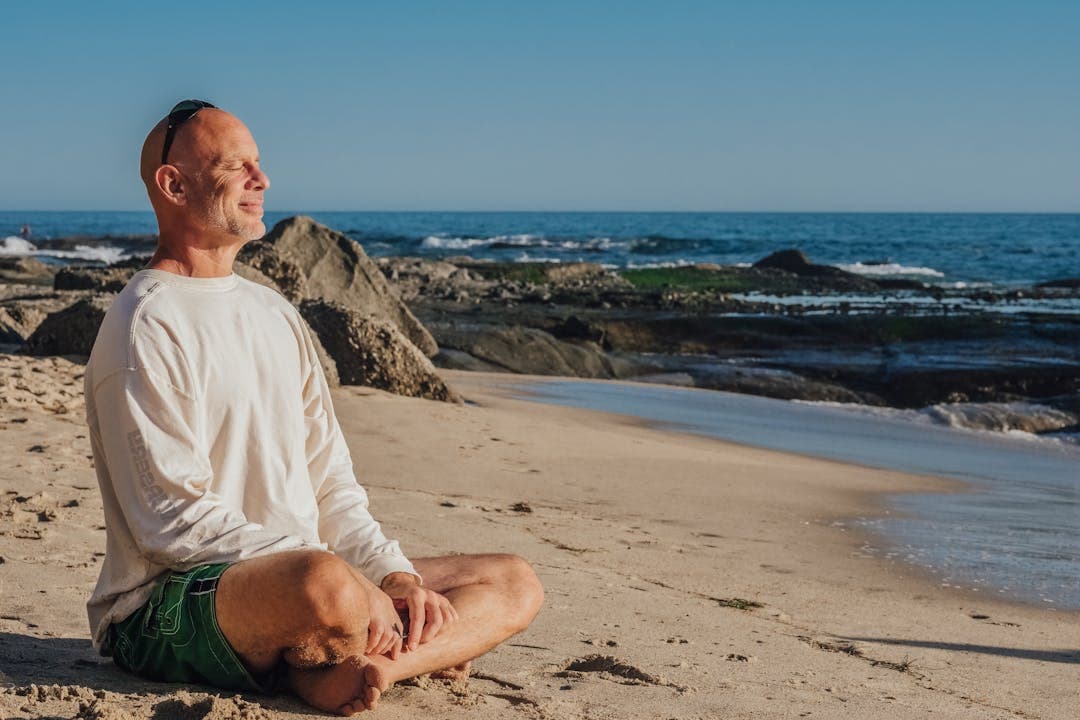 해변에서 명상 중인 시니어 남성, 은퇴 후 창업 준비의 여유로운 모습