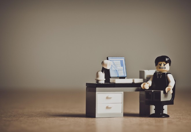 lego man sitting at a desk chair looking embarrassed and scared.