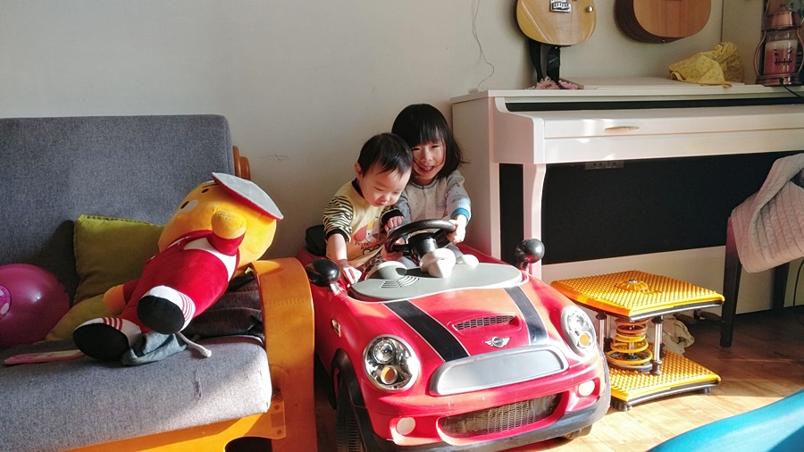 거실에서 전동자동차를 타는 아기들