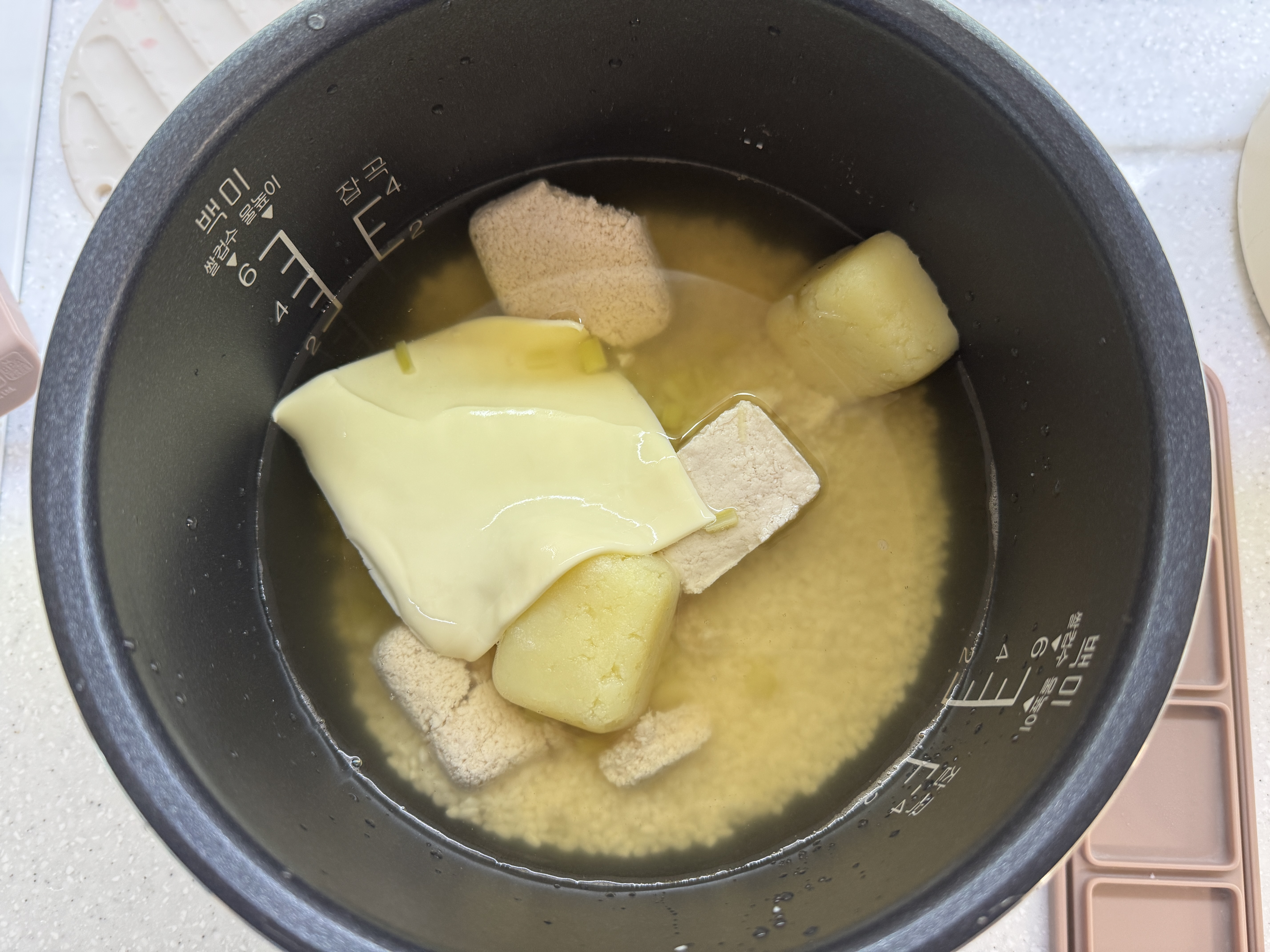 밥솥에 닭고기, 감자, 치즈, 아스파라거스를 넣은 사진