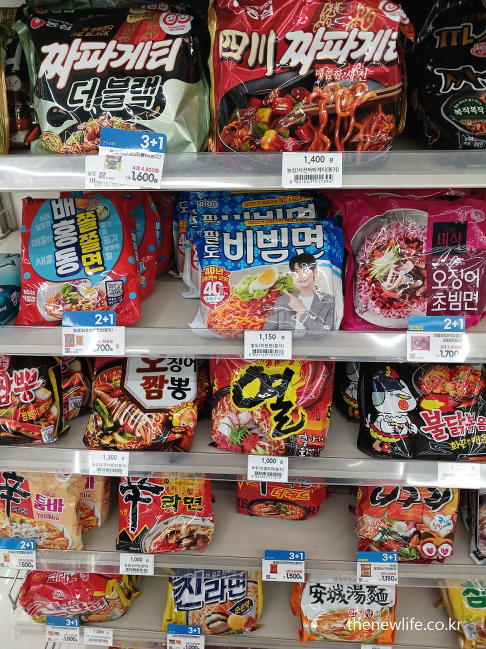 A supermarket ramen shelf with colorful Korean instant noodles such as Jjapagetti, Buldak, Bibim-myeon, and Shin Ramyun arranged in rows./한국의 다양한 라면이 진열된 마트 선반 – 짜파게티, 불닭볶음면, 비빔면, 신라면 등 컬러풀한 포장이 특징