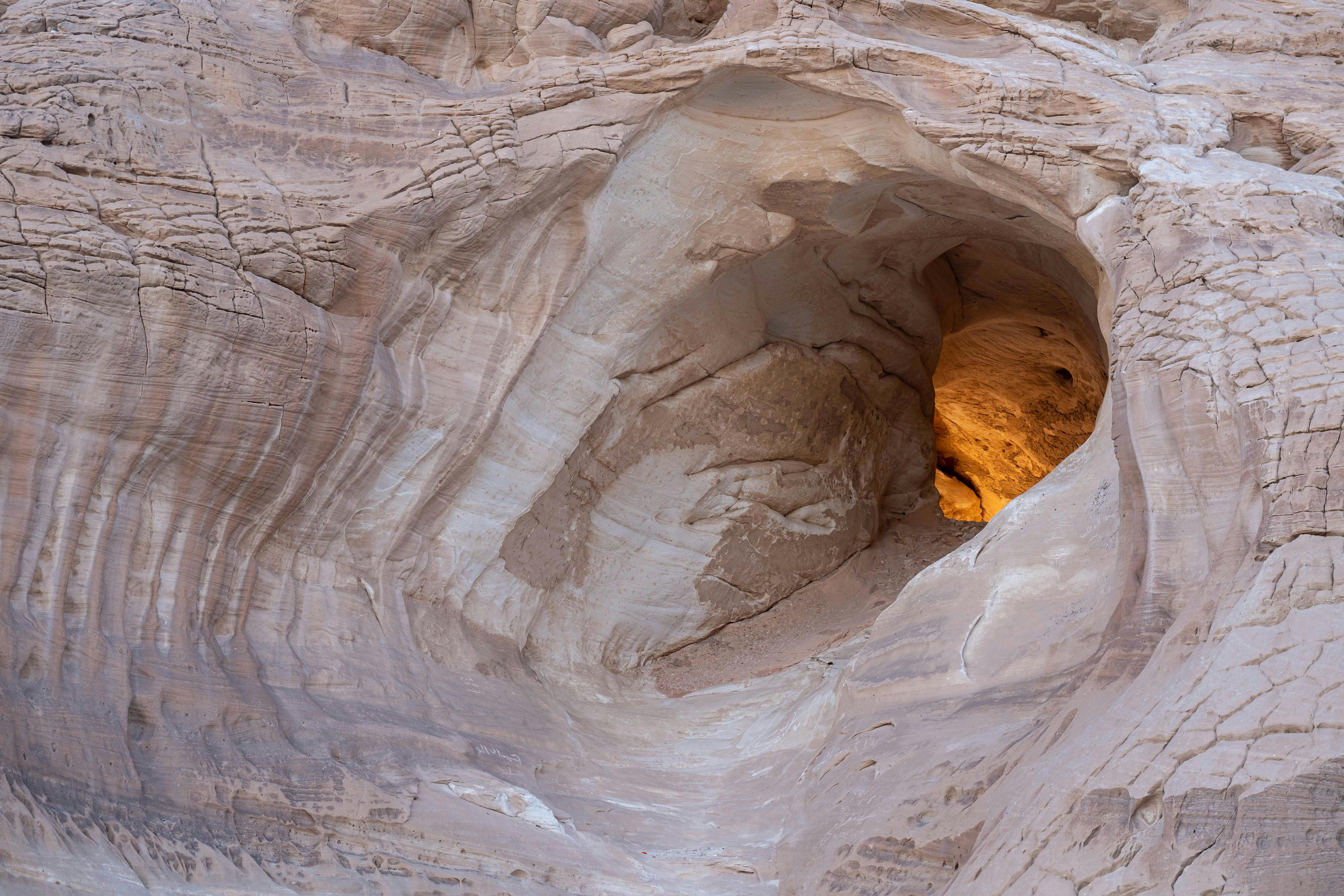 헤드램프 빛 아래 동굴 바닥 퇴적물과 벽 틈 주변 미세 서식지(이동 흔적이 점&middot;띠로 남는 구간)