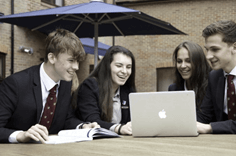 노트북을 보며 즐거운 표정으로 토론하는 4명의 영국 학생들
