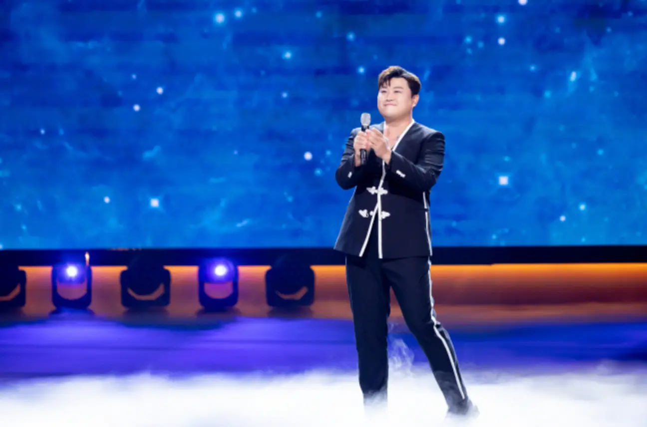 파란 무대 위 검은 양복을 입고 노래하는 김호중