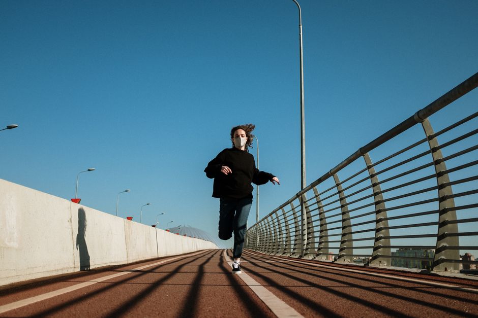 Individual running on a bridge with a mask, capturing urban routine during the pandemic.
