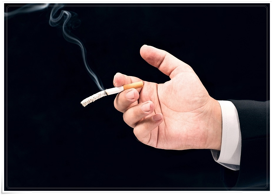 손가락 사이에서 타고 있는 담배와 공중으로 흩날리는 담배 연기를 찍은 모습