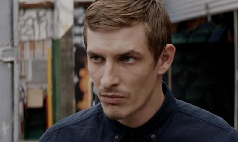 남색 티셔츠를 입고 어딘가를 무섭게 바라보고 있는 갈색머리의 미션 임파서블 7 출연진 프레드릭 슈미트