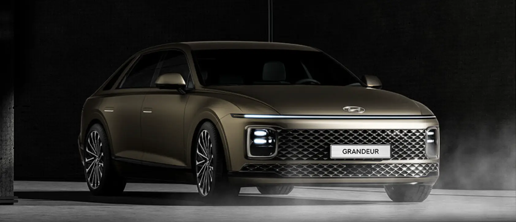 어두운 배경 회색 시멘트 바닥 위 빛나는 갈색 그랜저 차량의 옆모습