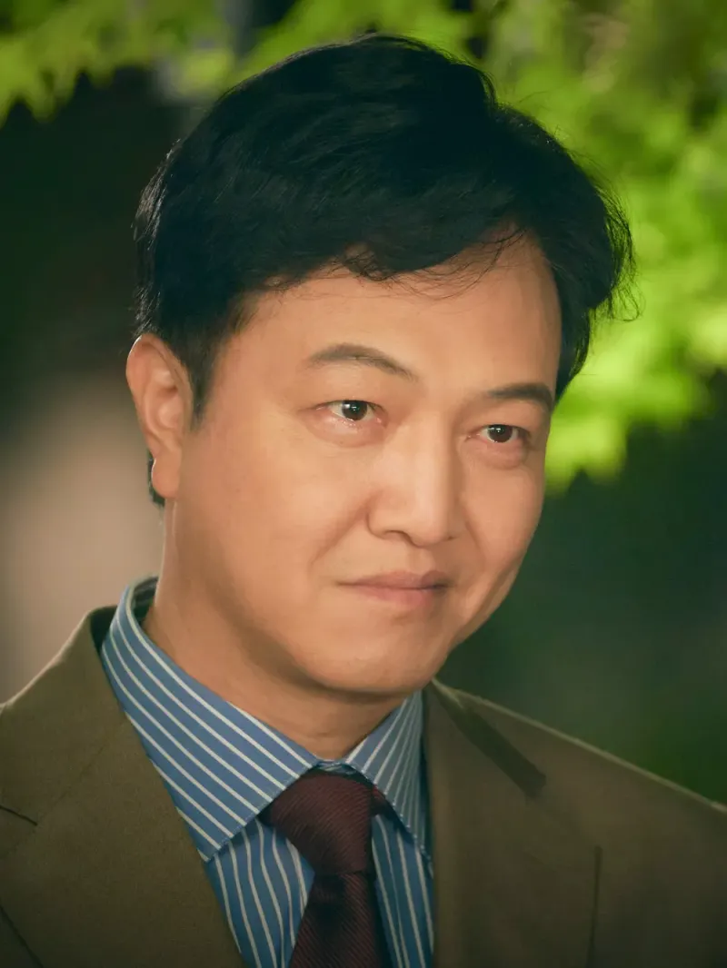 카키색 정장을 입고 웃고 있는 드라마 낮에 뜨는 달의 석철환 캐릭터