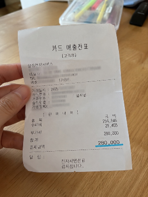 태블릿 수리비가 표시된 서비스센터 영수증을 손에 들고 있는 모습