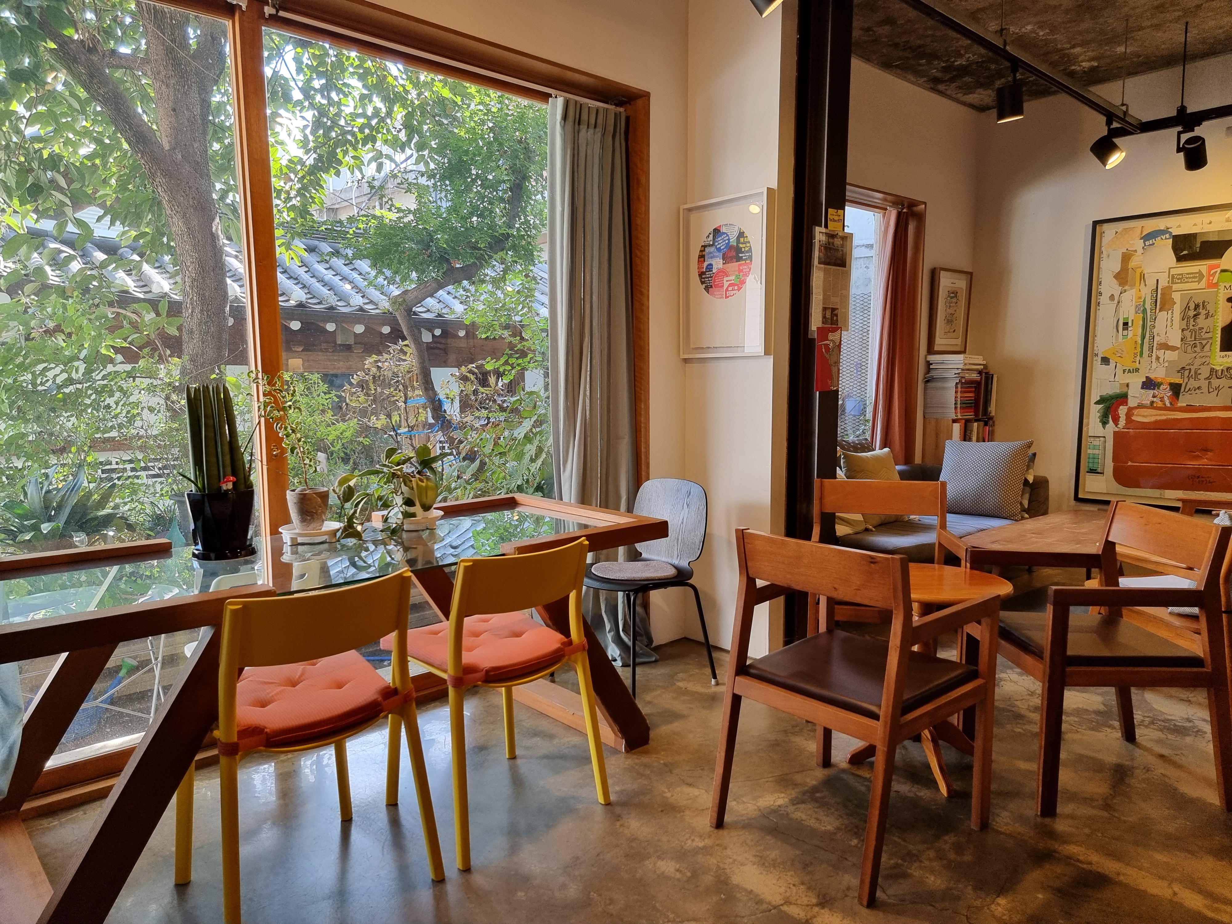카페-내부-큰창문밖-기와지붕-나무풍경-테이블
