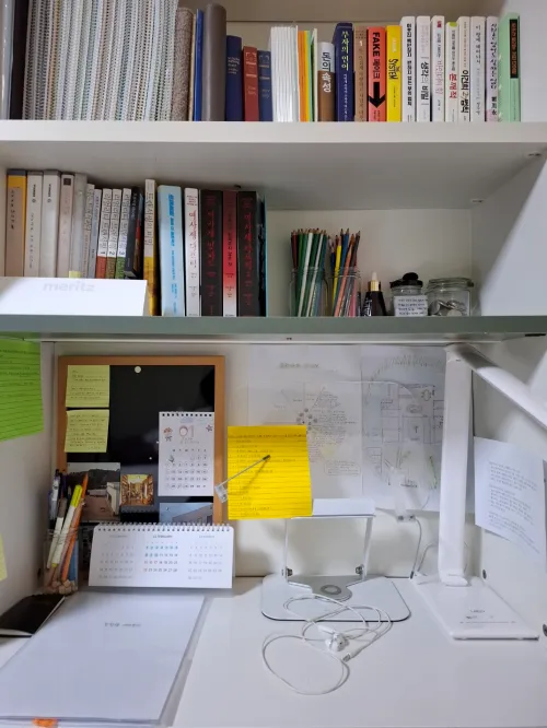 의도의 상징물인 작은 수첩과 인형이 놓여 있는 정갈한 책상 (A neat desk with a small notebook and a doll, which are symbols of intention)