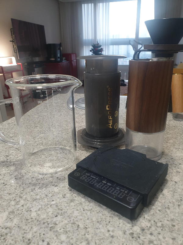 테이블 위에 에어로프레소와 코만단테 그라인더 그리고 서버와 저울이 올려져 있다.