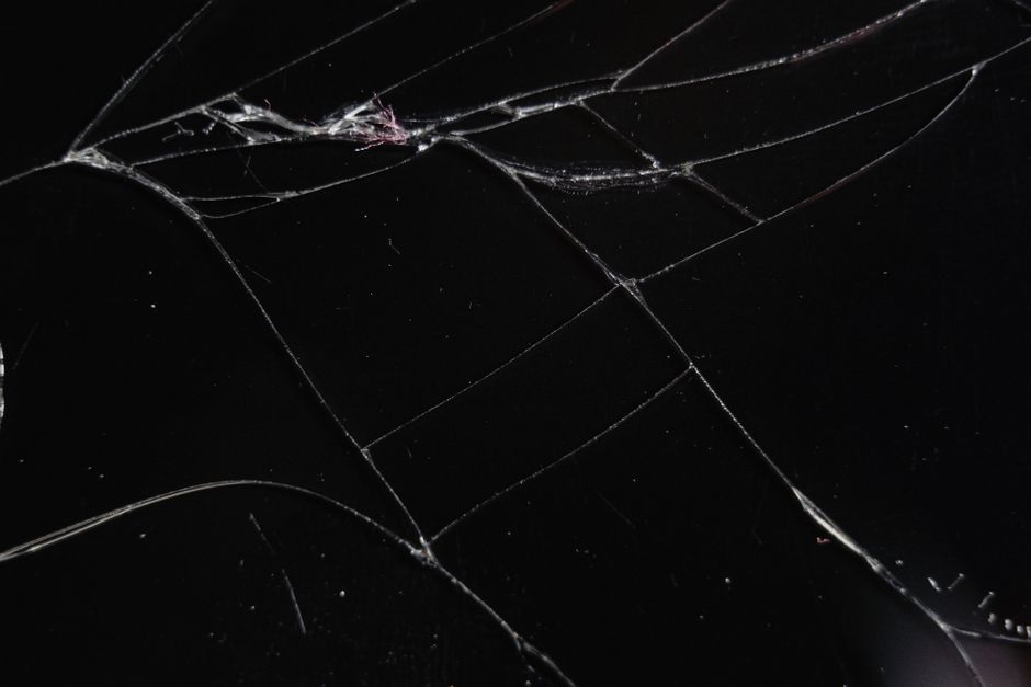 Close-up of a cracked glass surface displaying intricate patterns and reflections.