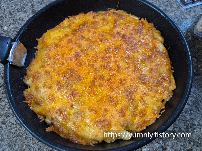 Homemade french fry pizza with melted, golden-brown crispy cheese in a pan