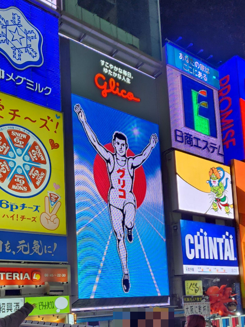 두 손을 들고 뛰는 남성 네온 사인 글리코.가 크게 보인다.