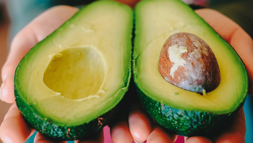 반으로 갈라져 있는 아보카도를 양손에 들고 있다