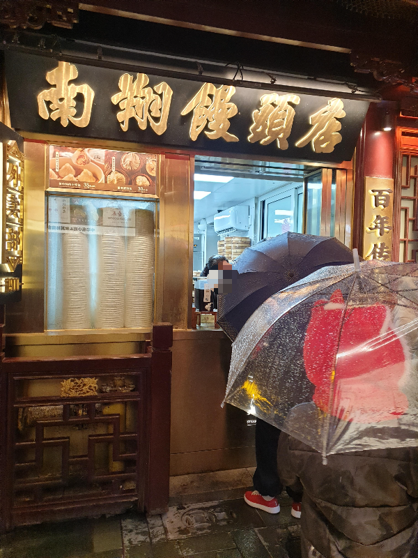 우산을 쓴 사람들이 남상 만두를 테이크 아웃 주문하고 있다.