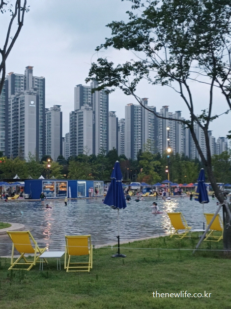 노란 썬베드와 파란 파라솔, 그리고 잠실 한강공원 물놀이장 주변 편의시설이 잘 갖춰진 풍경