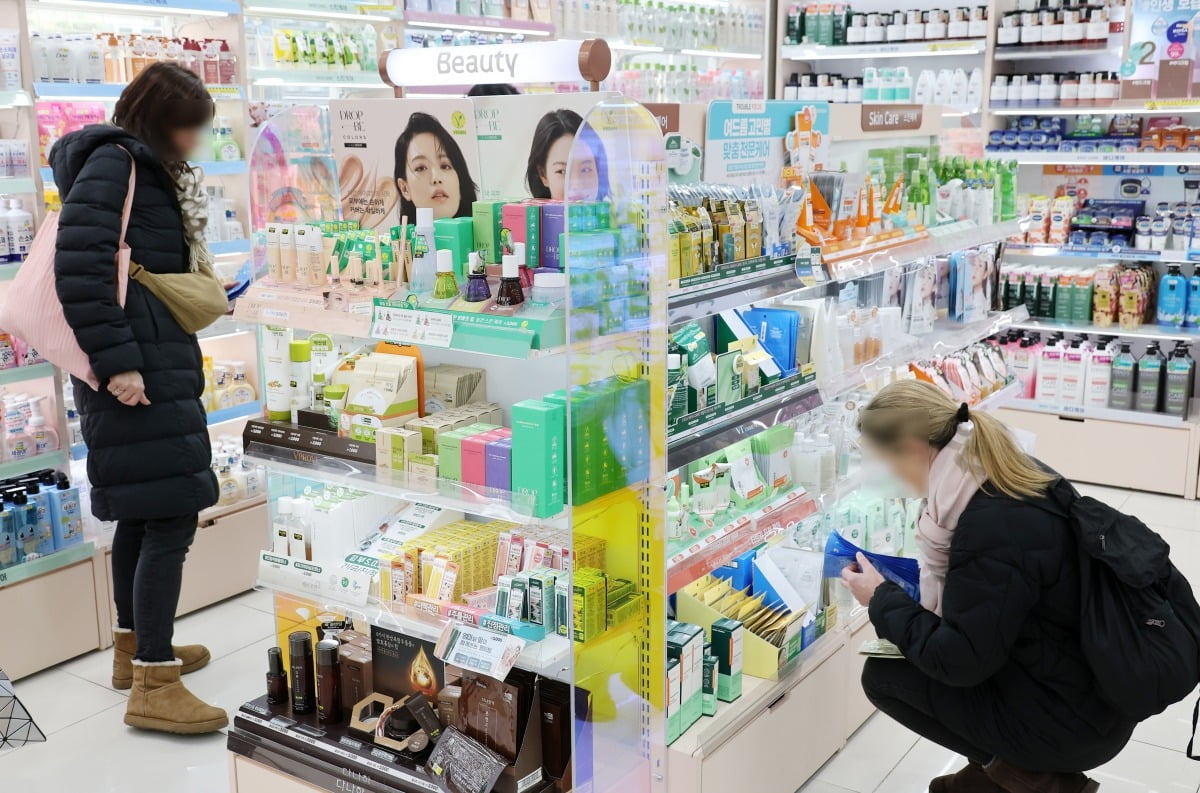 다이소 뷰티 제품을 둘러보는 외국인 관광객 모습.