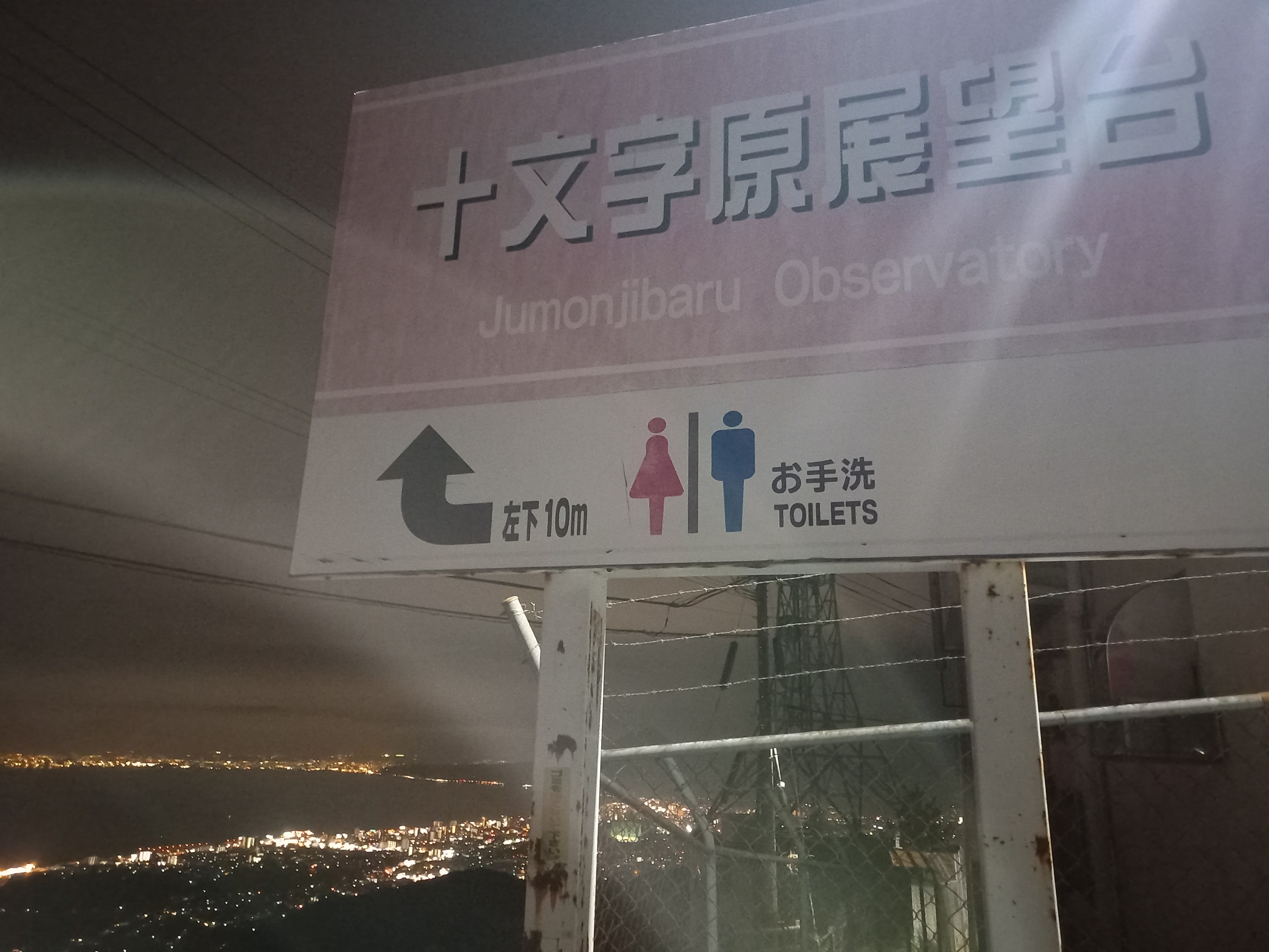 쥬몬지바루전망대의 간판과 그 뒤의 야경