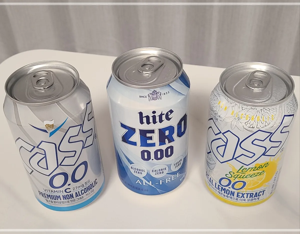 흰테이블 위 카스제로캔맥주 하이트제로캔맥주 카스레몬캔맥주를 위에서 올려다본 모습