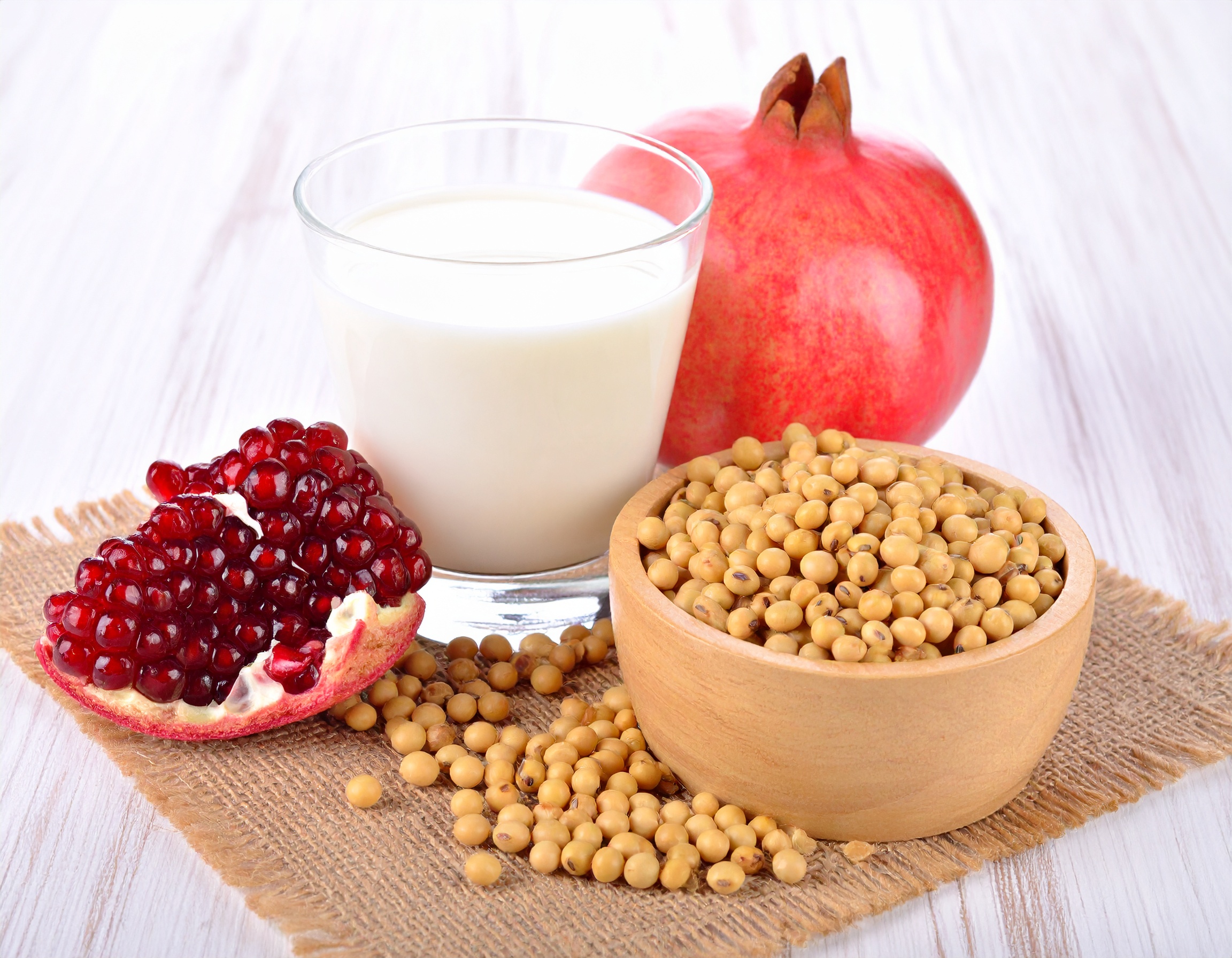 식물성 에스트로겐이 풍부한 콩, 두유, 석류를 나무 테이블 위에 놓은 건강한 식단 구성
