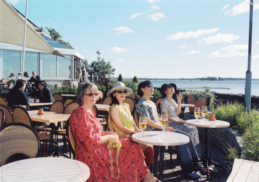 카페 야외 테라스에 앉아 있는 선글라스 낀 여자 네 명