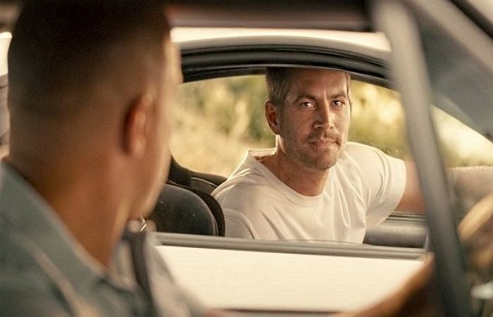 차에서 도미닉을 향해 미소지으며 바로보고 있는 브라이언