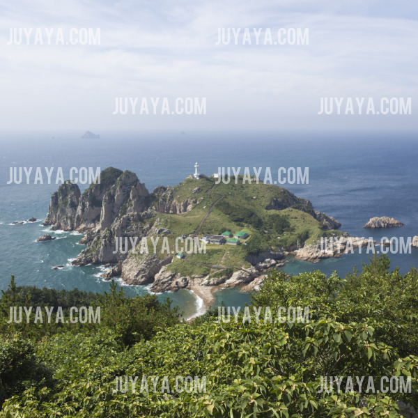 A panoramic view of Somaemuldo Island with a lighthouse standing tall on the cliff, surrounded by the clear sea and rocky terrain.