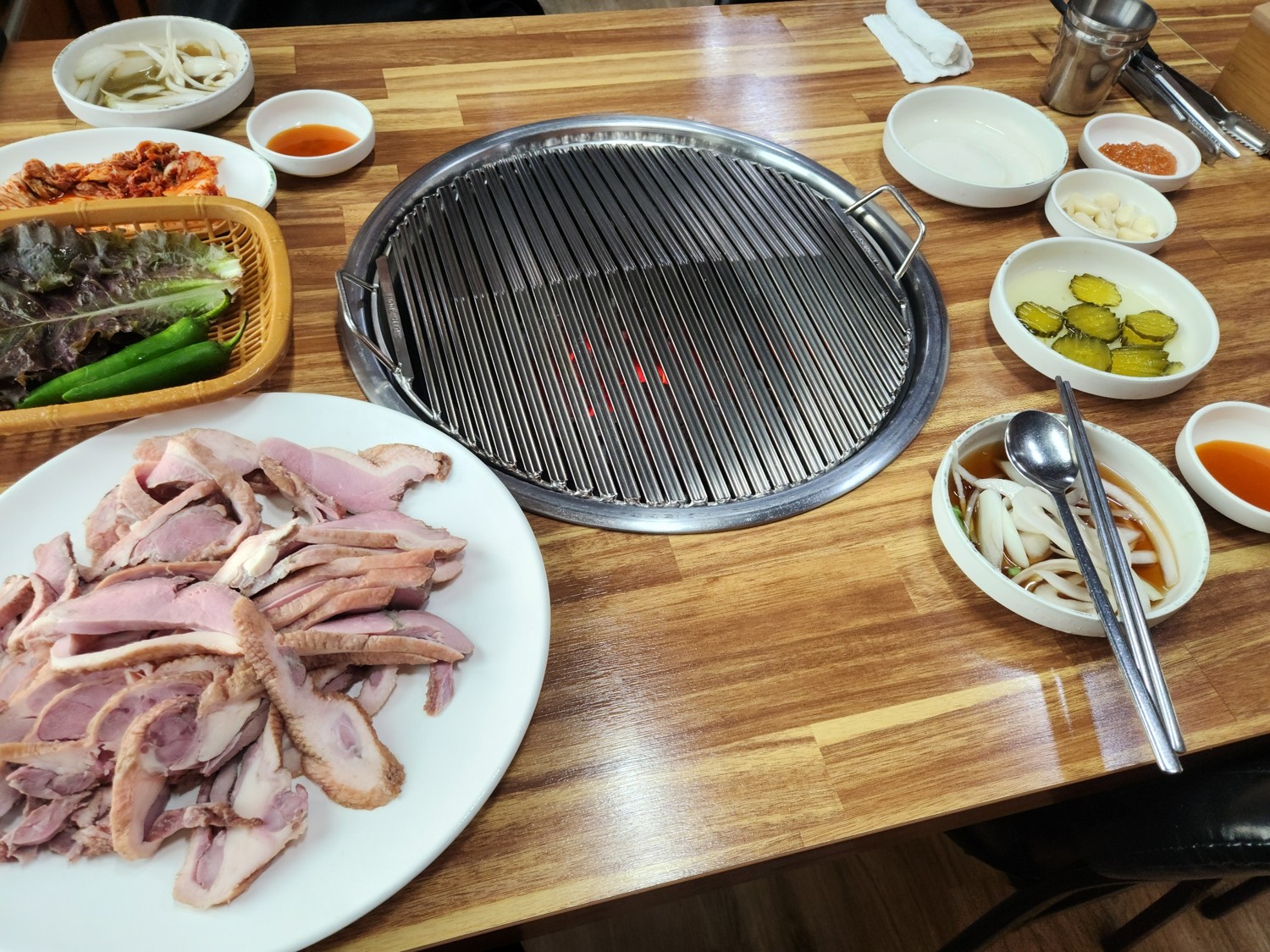 테이블 위에 오리 고기, 야채, 마늘, 양파 등이 올려져 있다