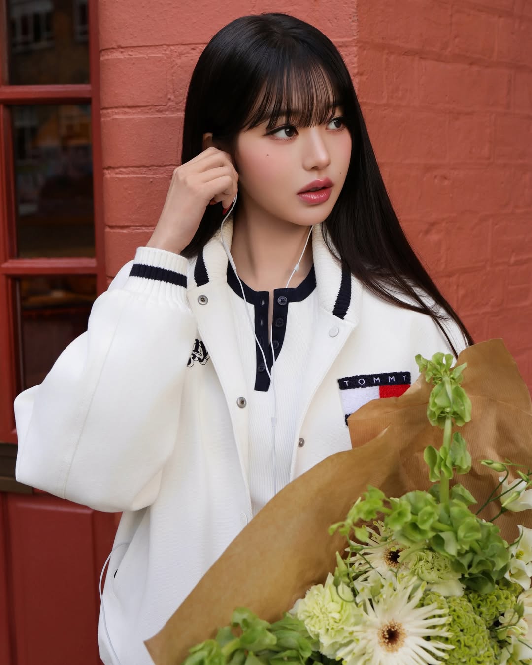 타미힐피거 자켓을 입고 이어폰을 끼고 있는 장원영의 모습