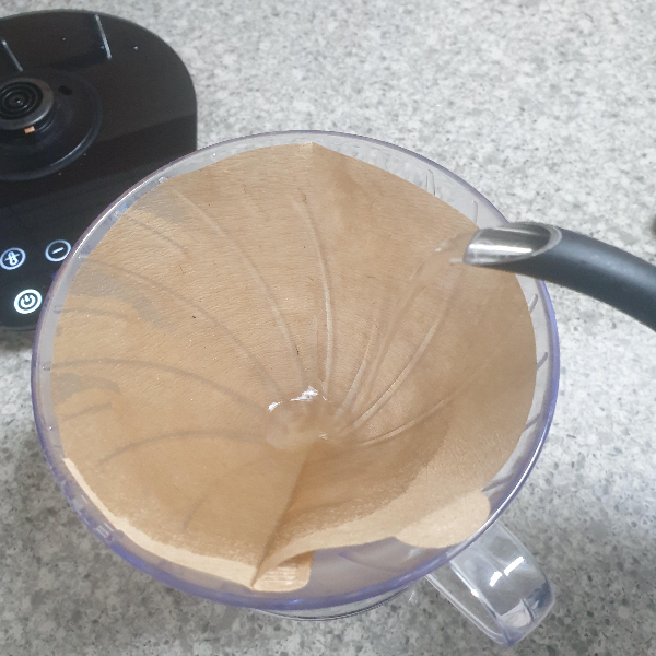 드리퍼에 황색 필터가 장착되어 있다. 물을 부어 필터를 린싱하고 있다.