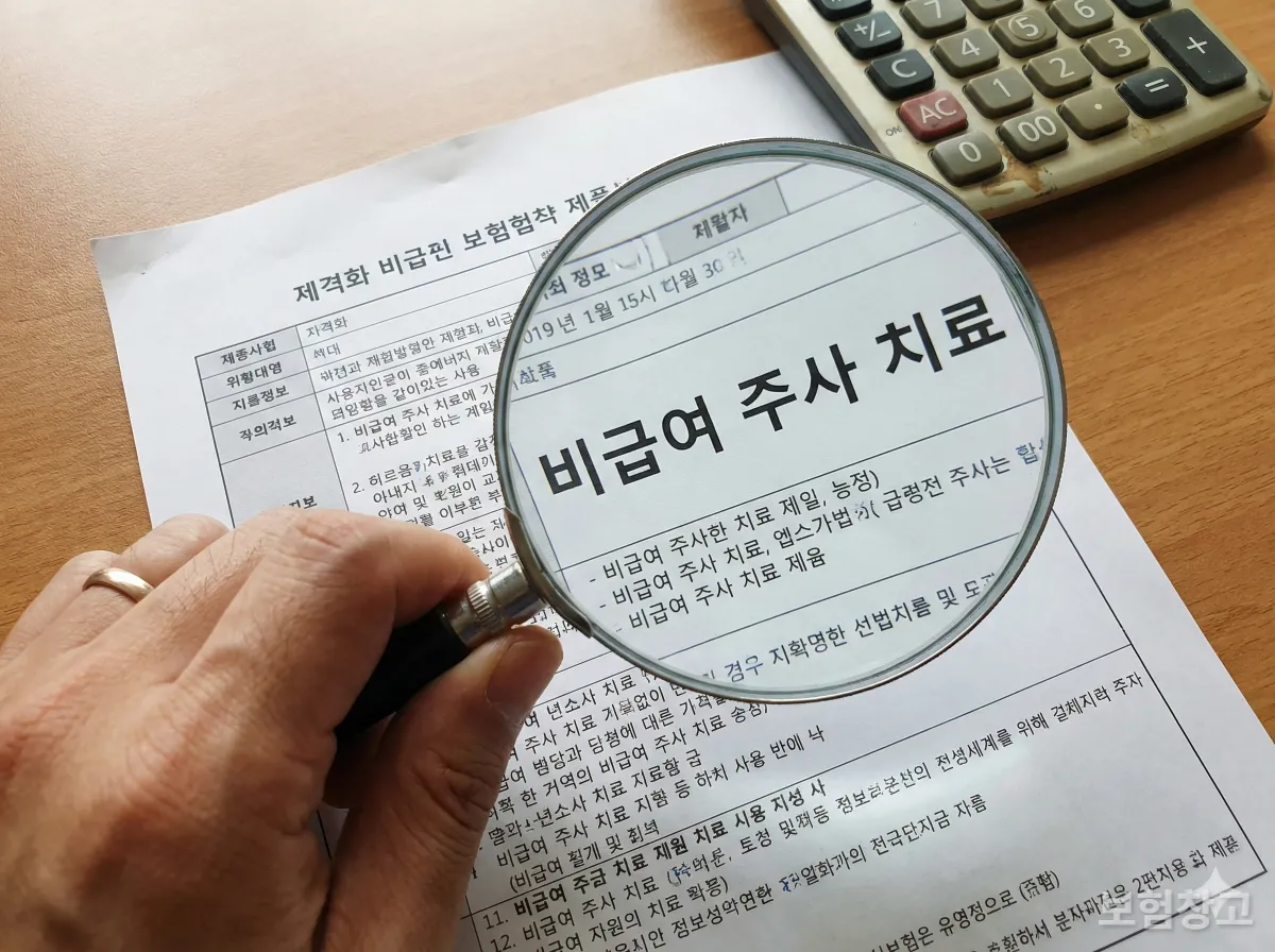 실손보험 약관의 비급여 주사제 보상 기준을 돋보기로 꼼꼼하게 확인하는 모습