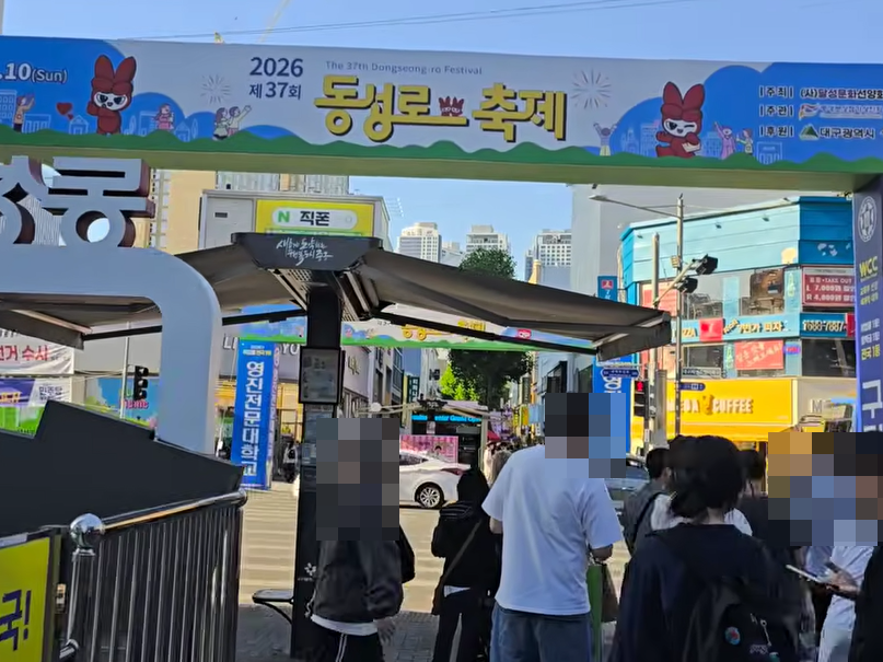 2026 제37회 동성로축제라고 적힌 대형 아치형 게이트 아래로 시민들이 지나가고, 뒤편에 동성로 상점 간판과 버스 정류장이 보이는 입구 전경