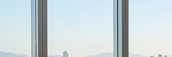 금리 인하 투자 성공을 상징하는 고급스럽고 미니멀한 개인 사무실 전경. 탁 트인 도시 전망과 정돈된 데스크가 어우러진 전문적인 분위기의 이미지