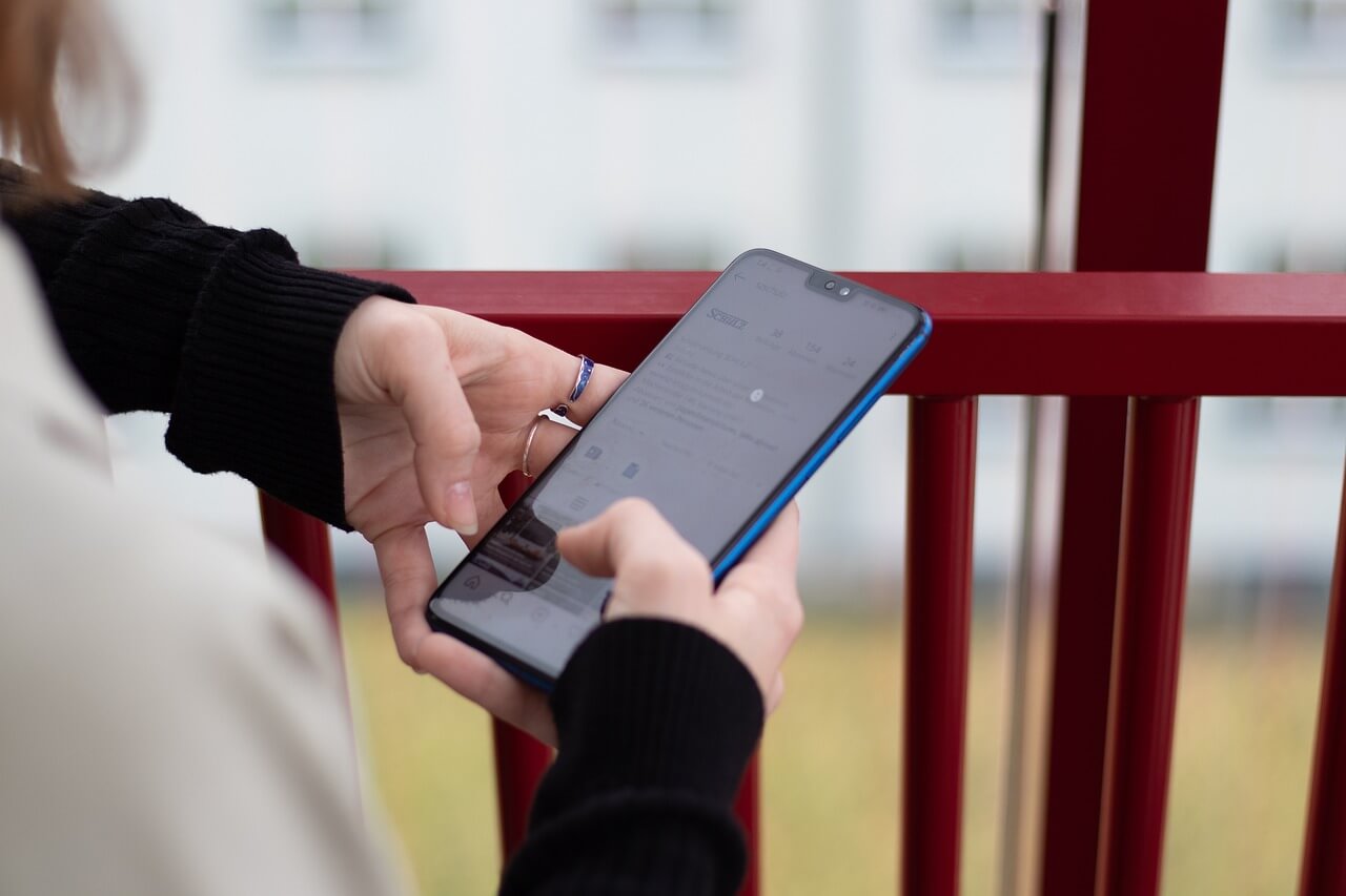 실외에서 모바일 화면을 조작하는 여성