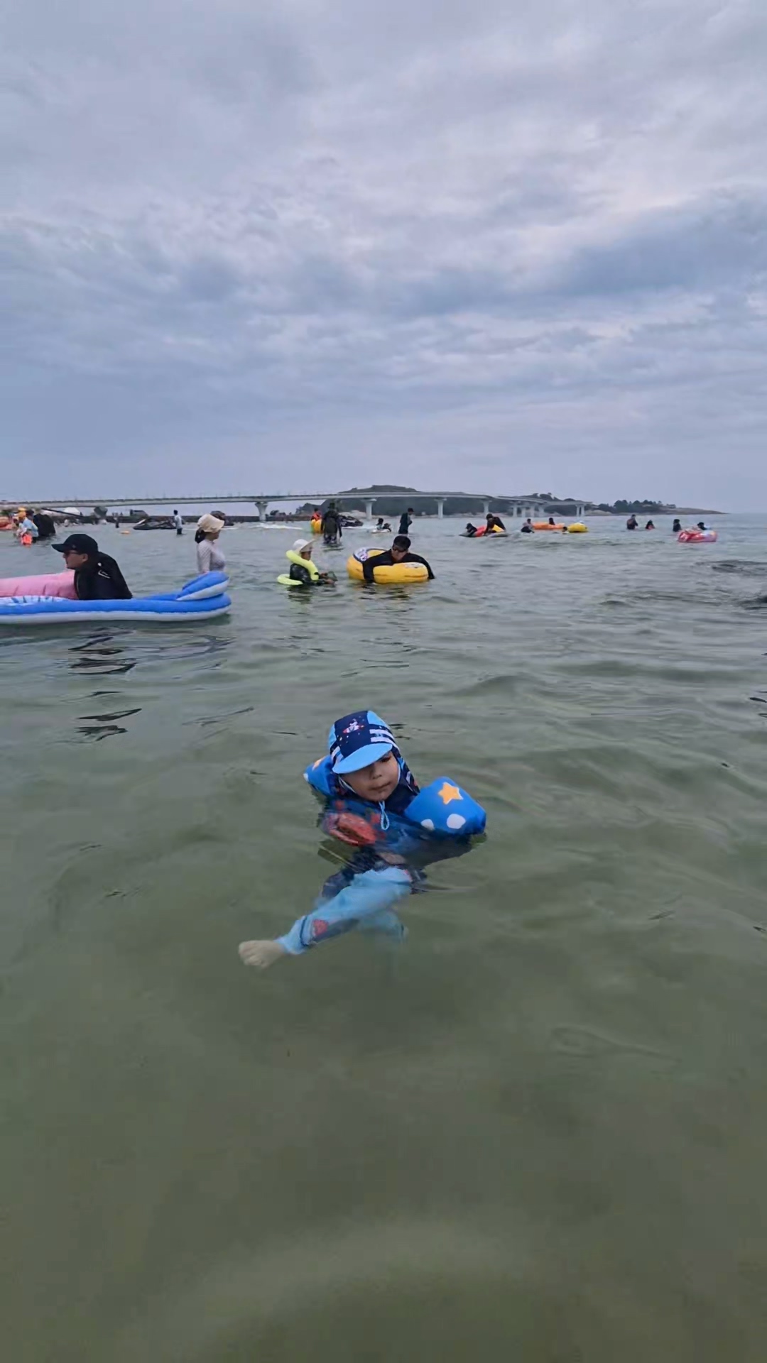 바다에서 구명조끼를 입고 재밌게 수영하고 있는 아이 사진