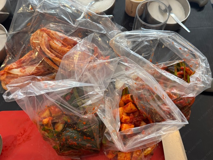 Three types of freshly made Korean Kimchi packed in plastic bags including cabbage cucumber and radish ❘ Trois types de Kimchi coréen fraîchement préparés et emballés dans des sacs en plastique chou concombre et radis