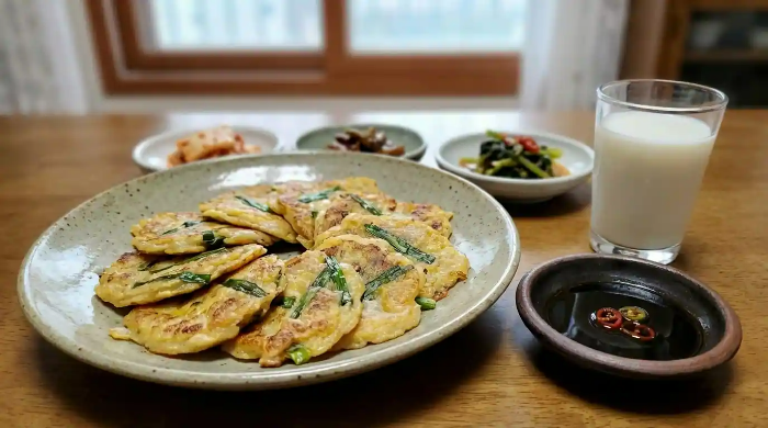 홍어전, 간장 종지, 우유 한잔이 식탁에 놓여 있음