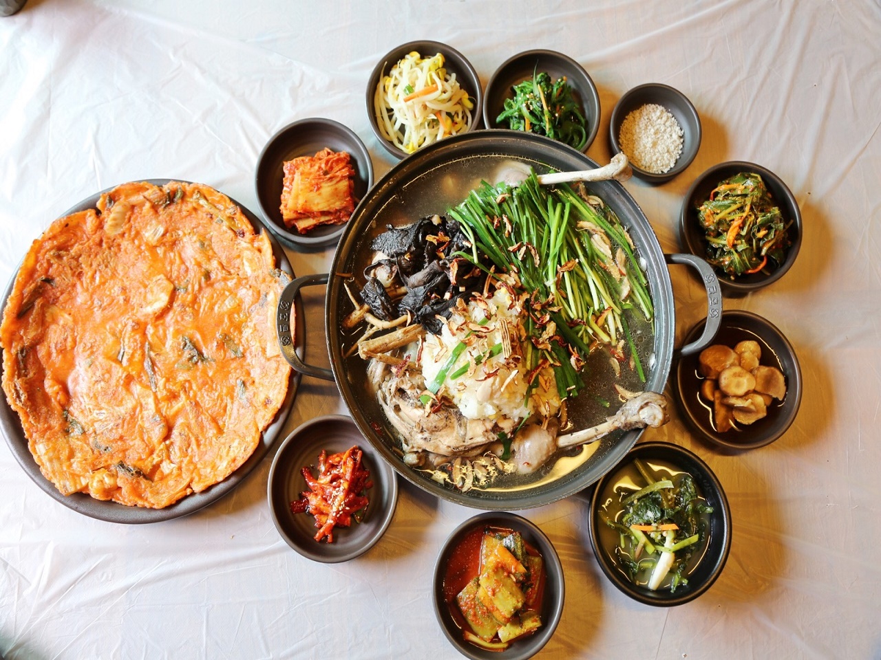 백숙과 김치전과 각종 밑반찬이 상에 놓인 사진