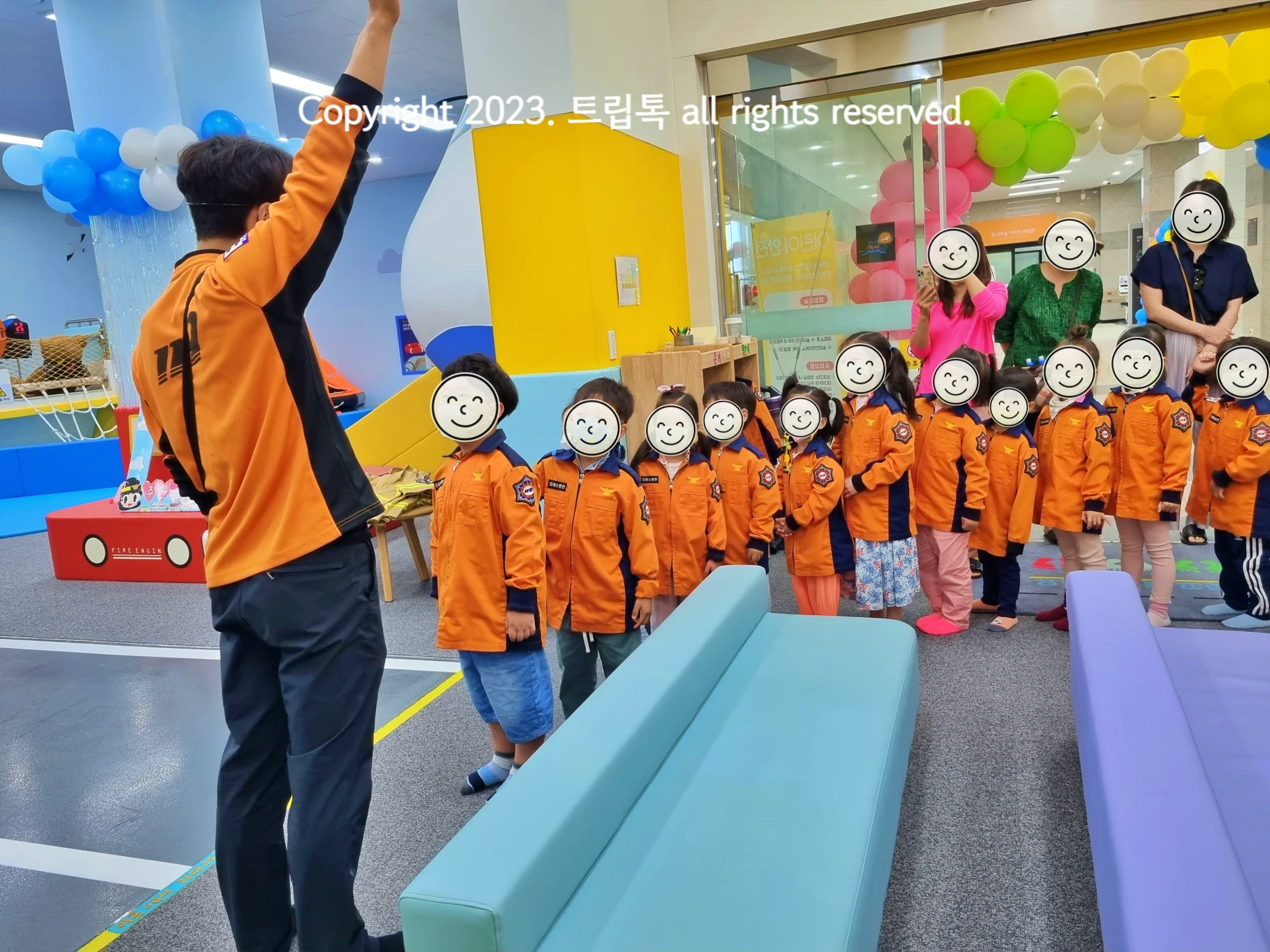 주황색 옷을 입은 선생님과 아이들이 수업하는 모습