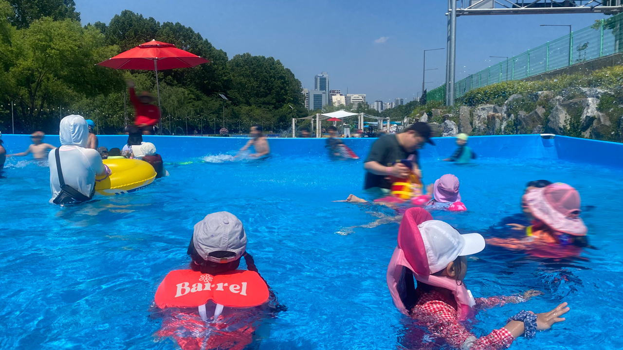 양재천 수영장의 성인풀에 아이들과 어른들이 함께 물놀이를 하고있다