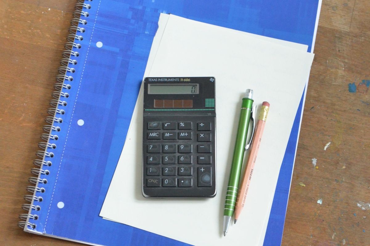 calculator notebook pen on wooden table