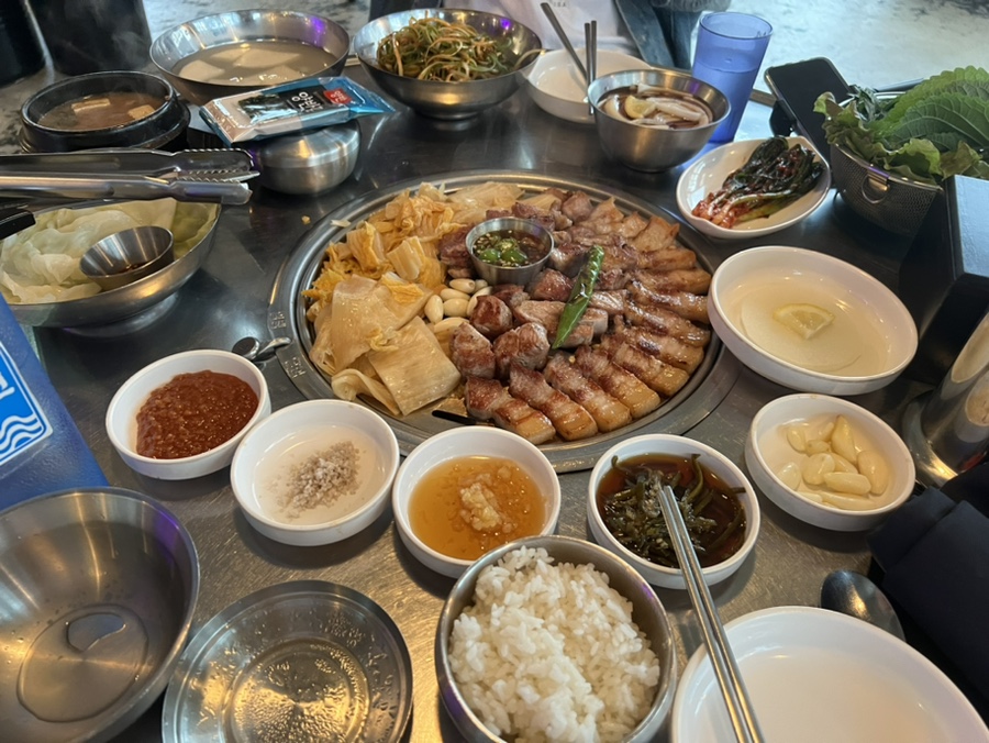 기장 삼겹살 맛집 부산댁의 대표 한상차림, 삼겹살과 다양한 밑반찬이 풍성하게 차려진 메인 대표 사진