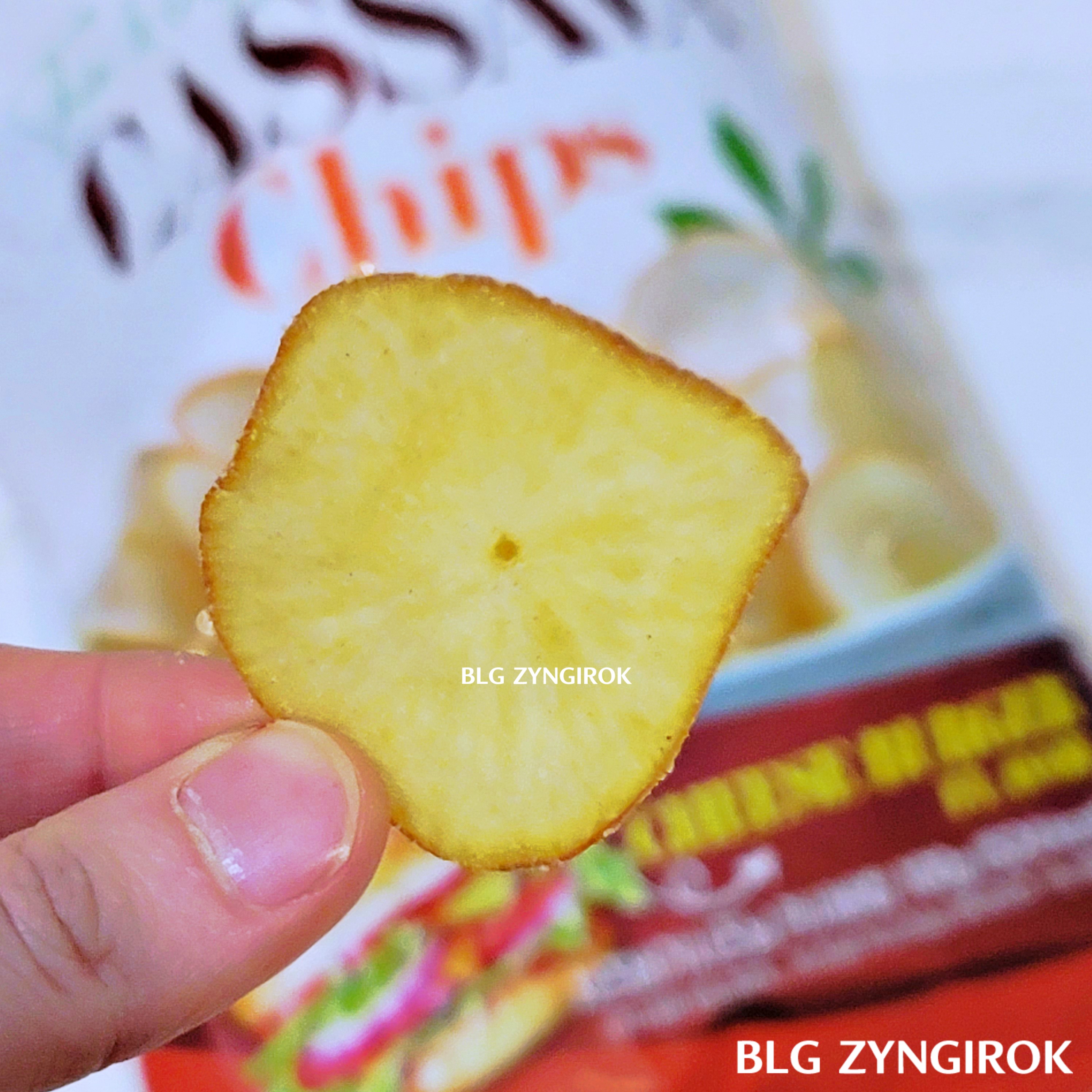 노브랜드 판매중인 카사바칩 - 카사바칩 치즈버거시즈닝 칩 한 개를 들고있다.