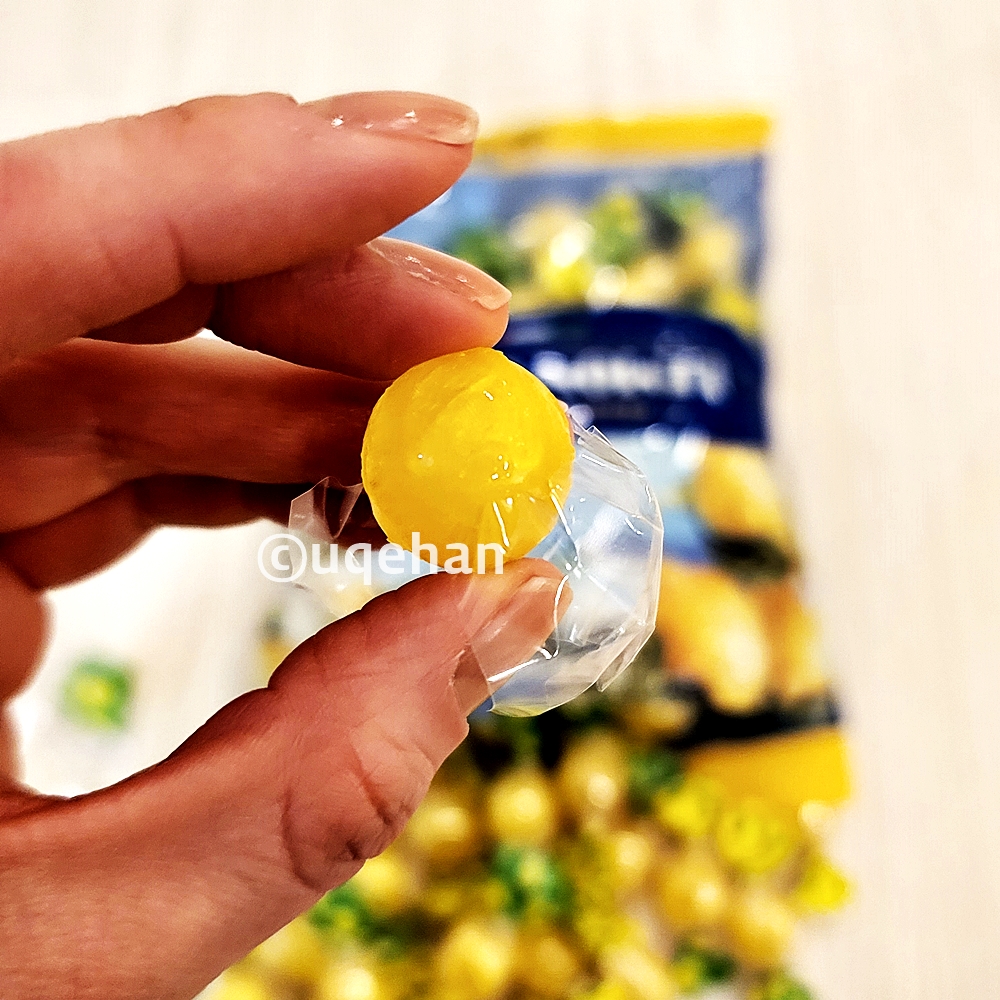 노브랜드 레몬캔디를 2번의 투명 비닐을 벗겨낸 사진이다. 손으로 노란색 캔디를 쥐고 있다.