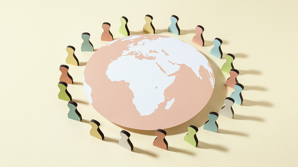 분홍색 지구를 둘러싼 다양한 색깔의 사람 모양 종이 인형들