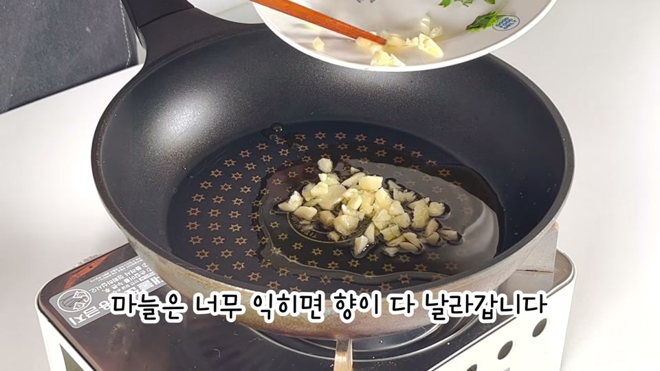 팬에 올리브오일과 마늘을 넣어 볶는 장면