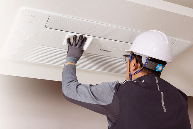 삼성에어컨 청소 예약 및 비용과 관련하여 삼성전문 엔지니어가 벽걸이에어컨을 청소하고 있는 사진